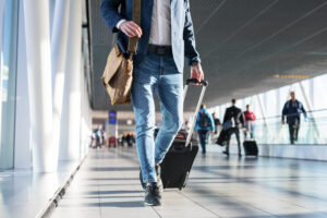 Man,With,Shoulder,Bag,And,Hand,Luggage,Walking,In,Airport