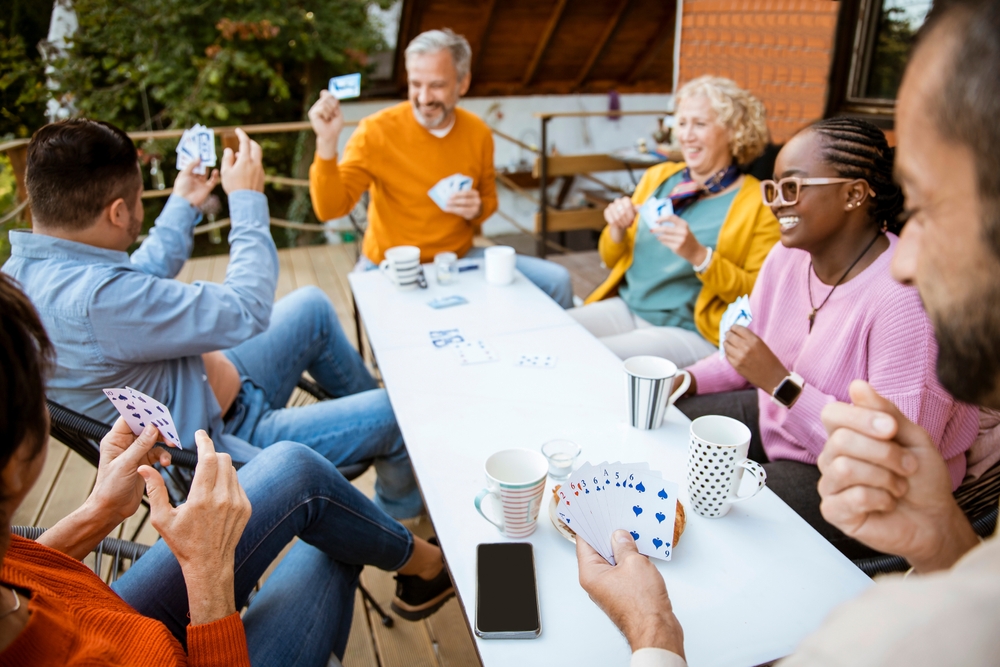 Elderly,Diverse,People,Playing,Cards,Outside,In,Home,Patio.,Happy