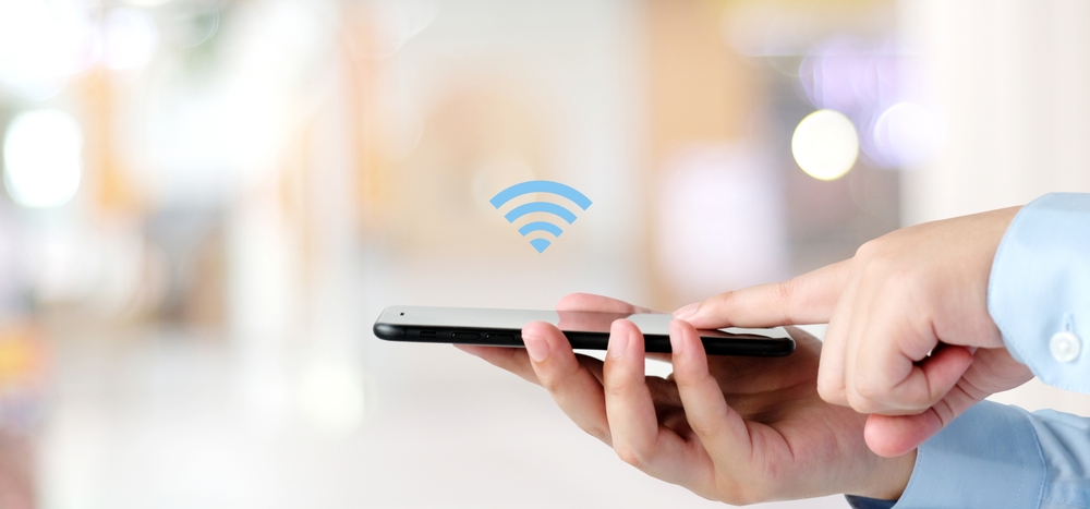 Hand,Holding,Mobile,Phone,With,Wifi,Icon,Over,Blur,Background