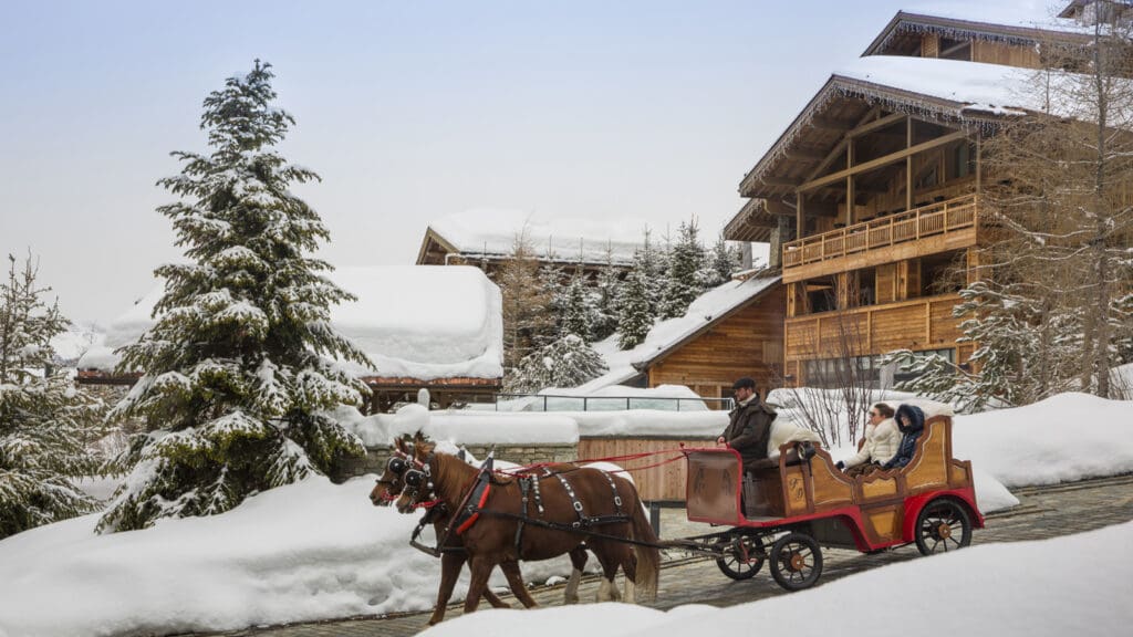 Four Seasons Megève resort in snow with skiers on the slopes of Mont d'Arbois below Mont Blanc