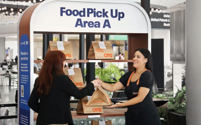 Passenger collecting a United gate food delivery order from a pickup shelf in Newark Terminal C