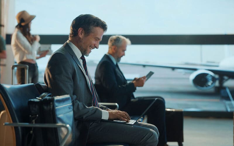 Business traveller working on a laptop in an airport lounge, illustrating business travel planning tips for work trips
